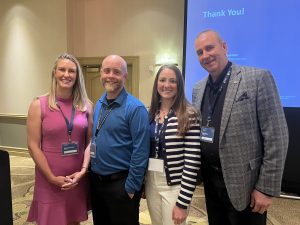 four individuals pictured smiling at conference in Indiana. 