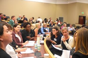 Attendees at the 2025 MHA Communications Retreat on Oct. 1, 2025, gather in a lecture hall for small group discussions. Participants are seated in clusters, reviewing papers, taking notes, and collaborating in an interactive session.