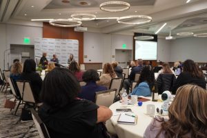 Conference attendees seated at round tables listen to speakers at the front of the room during the MHA Human Resources Conference.
