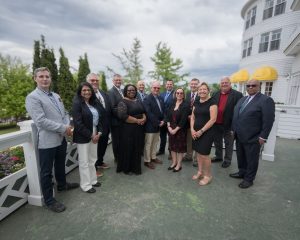 Group photo of the 13 graduates of the 2025-26 MHA Excellence in Governance Fellowship standing outdoors following their graduation ceremony.